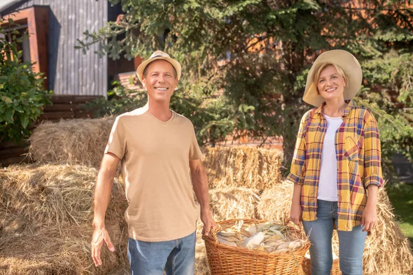 トウモロコシの穂軸を持った籠を持った男女の農家 — ストック写真