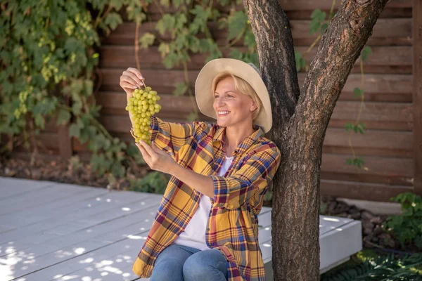 Glimlachend vrouwtje dat zich tegoed doet aan een tros groene druiven — Stockfoto