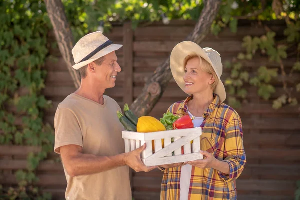 Мужчины и женщины-фермеры держат корзину с овощами — стоковое фото