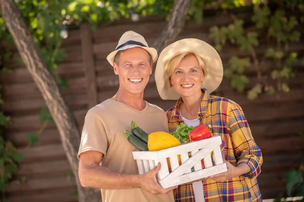 Campesinos y campesinas sonrientes sosteniendo canasta con verduras — Foto de Stock