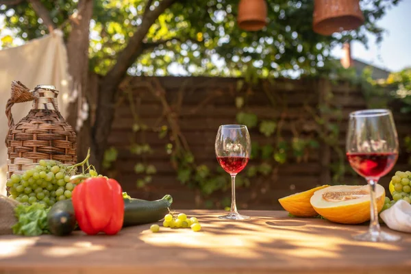 Два бокала красного вина на столе с фруктами и овощами — стоковое фото