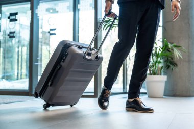 İş adamı. Resmi kıyafetli bir adam iş merkezine girerken bavul taşıyor.