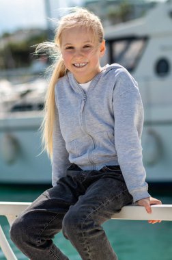 Sarışın kız güneşli bir günde rıhtımda yat ve denizle oturuyor.