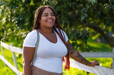 Plus size female with tattoo arm enjoying walk in green park