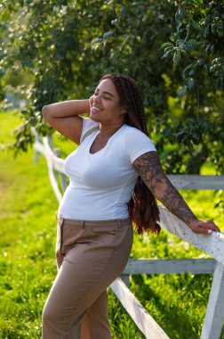 Happy African American woman on summer stroll surrounded by trees and sunshine
