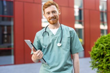 Young adult man medic with beard standing confidently with closed laptop