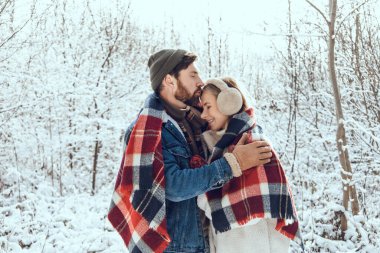 Ormanda yürü. Erkek ve kadın, kış ormanlarında kareli kareli kumaşın altında huzurlu ve romantik hissediyorlar.