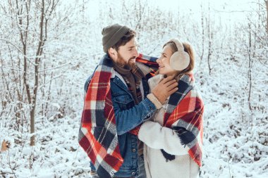 Ormanda yürü. Erkek ve kadın, kış ormanlarında kareli kareli kumaşın altında huzurlu ve romantik hissediyorlar.