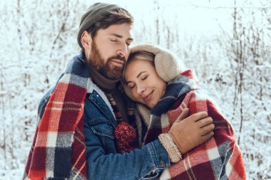 Ormanda yürü. Erkek ve kadın, kış ormanlarında kareli kareli kumaşın altında huzurlu ve romantik hissediyorlar.
