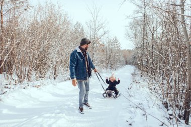 Kızak. Babası kızıyla birlikte kış ormanında kızağını çekiyor.