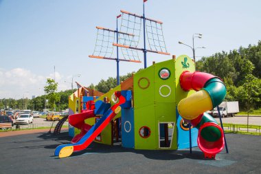 Wooden slides in the form of a ship of green and blue colors in the courtyard of a residential complex. Playgrounds, toys clipart