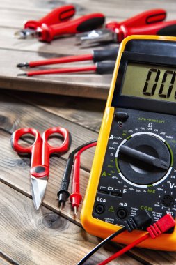 Multimetre, kelepçe, kablo kesici, makas ve bir antika ahşap masanın üzerinde fotoğrafı bir konut elektrik sistemi çalıştığı için Tornavidalar.