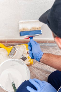 İşçi evi ressam bir boya fırçası ile beyaz bir duvar boyama iş başında