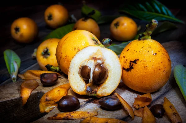 Close-up of freshly harvested fresh medlars on an antique wooden table, photographed in light painting