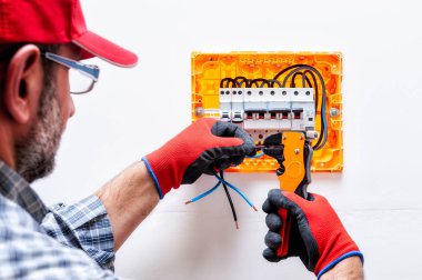 Elektrikçi teknisyen eldiven korumalı el ile çalışır bir konut elektrik panel tel makası kerpetenle.