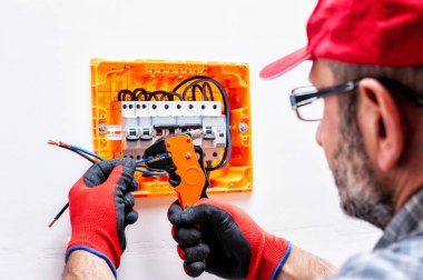 Elektrikçi teknisyen eldiven korumalı el ile çalışır bir konut elektrik panel tel makası kerpetenle.