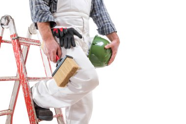 House painter worker on the ladder with white work overalls, keeps the brush for painting in his hand. Equipped with shoes, helmet and protective gloves. Isolated on white background. Text space