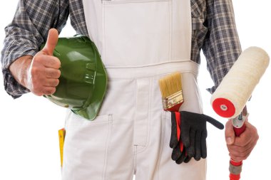 Beyaz iş tulumu giymiş boyacı başparmağı havada, elinde boya yapmak için silindiri tutuyor. Koruyucu eldivenlerle donatılmış. Beyaz arka planda izole edilmiş. İnşaat endüstrisi.