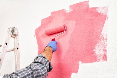 Beyaz Beyaz Saray ressam işçi iş Tulum, silindir ile o pembe renkli boyama duvar boyar. İnşaat sektöründe. Alt görünümü.