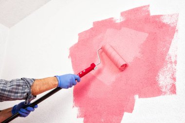 Beyaz Beyaz Saray ressam işçi iş Tulum, silindir ile o pembe renkli boyama duvar boyar. İnşaat sektöründe. Alt görünümü.