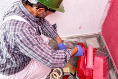 Beyaz Beyaz Saray ressam işçi iş Tulum, silindir ile o pembe renkli boyama duvar boyar. İnşaat sektöründe. Üstten görünüm.