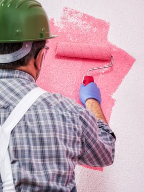 Beyaz Beyaz Saray ressam işçi iş tulum, silindir ile o pembe renkli boyama duvar boyar. İnşaat sektöründe. İş güvenliği. 