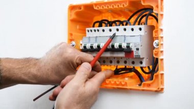 Bir konut montajı elektrik panelinde bir devre kesici kablo ekler ve engeller elektrikçi teknisyeninin elleri video. İnşaat endüstrisi.