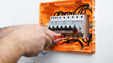 Bir konut montajı elektrik panelinde bir devre kesici kablo ekler ve engeller elektrikçi teknisyeninin elleri video. İnşaat endüstrisi.