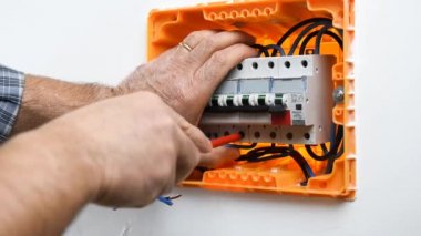 Bir konut montajı elektrik panelinde bir devre kesici kablo ekler ve engeller elektrikçi teknisyeninin elleri video. İnşaat endüstrisi.