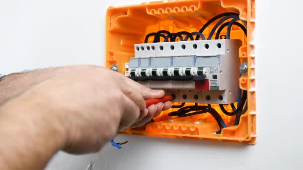 Vidéo des mains de l'électricien technicien qui insère et bloque le câble dans un disjoncteur dans le panneau électrique d'une installation résidentielle. Industrie du bâtiment .
