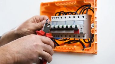 Elektrik kablolarını bir konut kurulumunun elektrik panelinde keserek elektrikçi teknisyeninin ellerinin videosu. İnşaat endüstrisi.