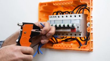 Tel striptizciler ile elektrikçi teknisyeninin ellerinin video bir konut montajı bir elektrik panelinde elektrik kabloları hazırlar. İnşaat endüstrisi.