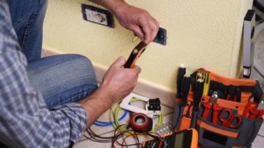 Elektrikçi teknisyeni işçi elektrik kablo hazırlar ve tornavida ile bu yuva konut elektrik sisteminde terminal için güvenlik altına alır. İnşaat sektöründe. Bina. Görüntüleri. 