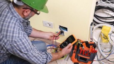Elektrikçi teknisyeni işçi multimetre ile bu yerleşim bir sistemde elektrik yuvasında gerilim ölçer. İnşaat sektöründe. Bina. Görüntüleri. 