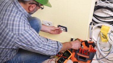 Elektrikçi teknisyeni işçi multimetre ile bu yerleşim bir sistemde elektrik yuvasında gerilim ölçer. İnşaat sektöründe. Bina. Görüntüleri. 