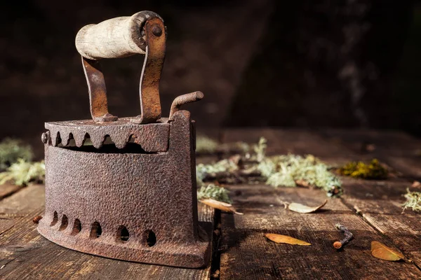 Ferro enferrujado velho em uma mesa de madeira rústica. Passar a ferro . — Fotografia de Stock