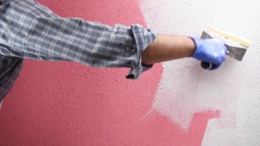 Beyaz tulumlu kafkas ev ressamı işçi, pembe duvarı fırça ile beyaz boya ile boyar. İnşaat sektörü. Görüntü.