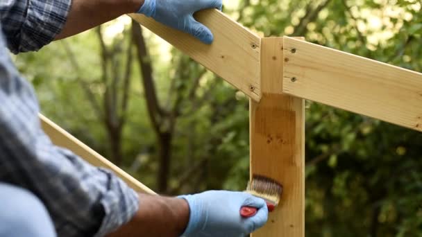 木製のフェンスの板を描くブラシを持つ大人の職人大工 家事は自分でやれ映像 — ストック動画