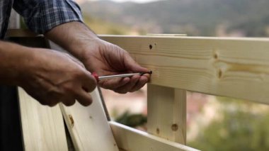 Tornavida ile Yetişkin marangoz ustası bir ahşap çit panoları düzeltmek için vida vida. Ev işleri kendin yap. Görüntü.