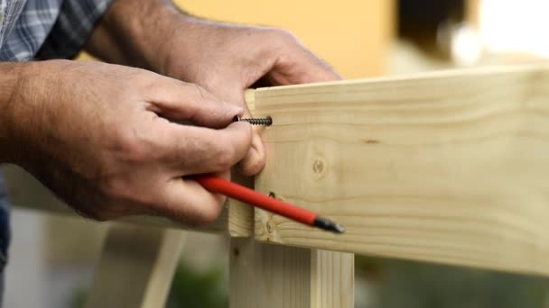 スクリュードライバー付きの大人の大工職人は 木製のフェンスのボードを固定するためにネジをねじ込みます 家事は自分でやれ映像 — ストック動画