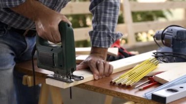 Elektrikli testere ile yetişkin zanaatkar marangoz ahşap bir masa kesme üzerinde çalışıyor. Ev işleri kendin yap. Görüntü.