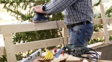 Elektrikli zıpzAma ile Yetişkin marangoz ustası ahşap bir çit panoları düzeltir. Ev işleri kendin yap. Görüntü.
