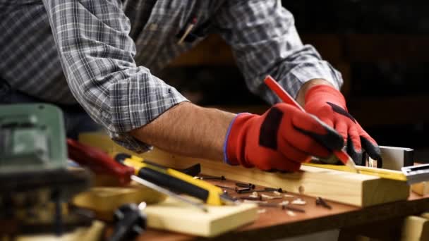 大人の大工職人は 鉛筆で保護手袋を着用し 大工の正方形は木製のテーブルの上に切断線をトレースします 建設業 家事は自分でやる — ストック動画