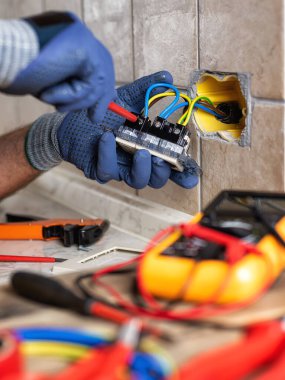 İşteki elektrikçi tornavidayla birlikte konut elektrik sisteminin prizlerini tamir ediyor. İnşaat endüstrisi. 