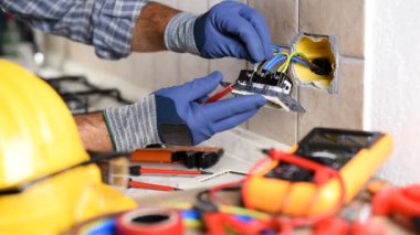İşteki elektrikçi tornavidayla birlikte konut elektrik sisteminin prizlerini tamir ediyor. İnşaat endüstrisi. Görüntü.