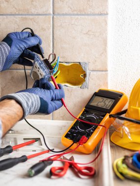 Elektrikçi, konut elektrik sisteminin prizlerindeki voltajı ölçüyor. İnşaat endüstrisi. 