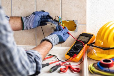 Elektrikçi, konut elektrik sisteminin prizlerindeki voltajı ölçüyor. İnşaat endüstrisi. 