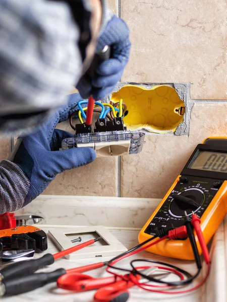 İşteki elektrikçi tornavidayla birlikte konut elektrik sisteminin prizlerini tamir ediyor. İnşaat endüstrisi. 