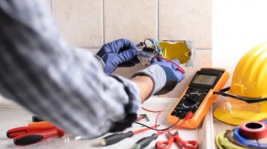 Elektrikçi, konut elektrik sisteminin prizlerindeki voltajı ölçüyor. İnşaat endüstrisi. Görüntü.