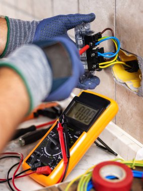 İşteki elektrikçi tornavidayla birlikte konut elektrik sisteminin prizlerini tamir ediyor. İnşaat endüstrisi. 